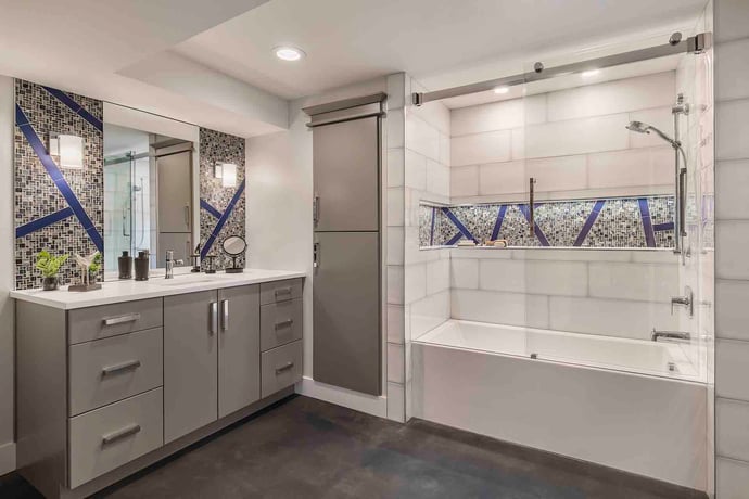 Remodeled basement bathroom featuring walk-in shower and tile backsplash by Creekstone Design + Remodel