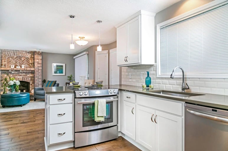 Remodeled kitchen with view of brick wall interior in living room by Creekstone Design + Remodel