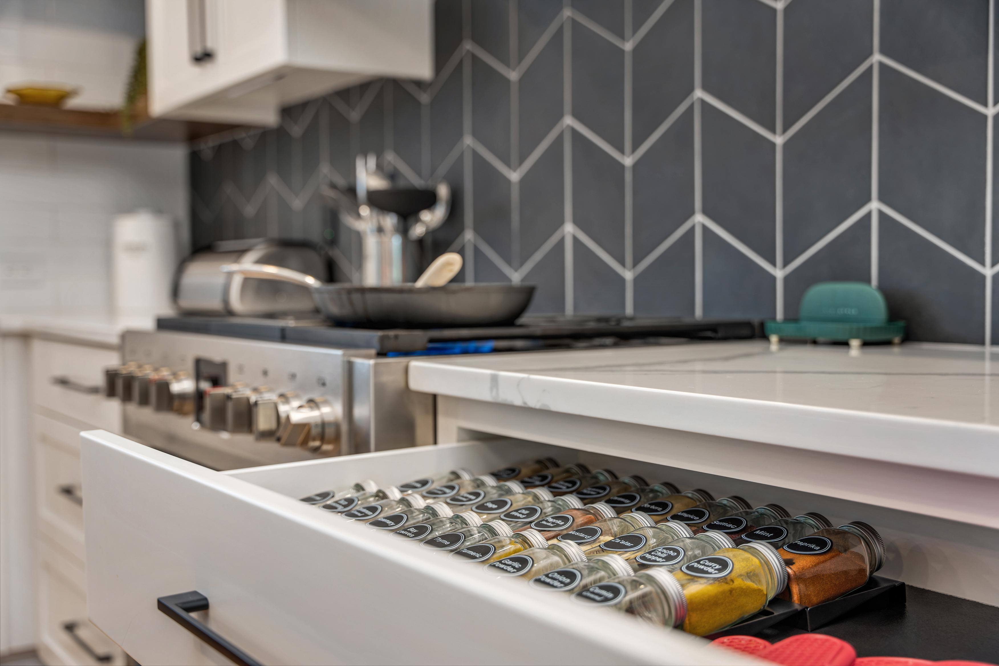 Southwest Hills Kitchen close view of spice drawer by stovetop area with gray backsplash by Creekstone Design + Remodel