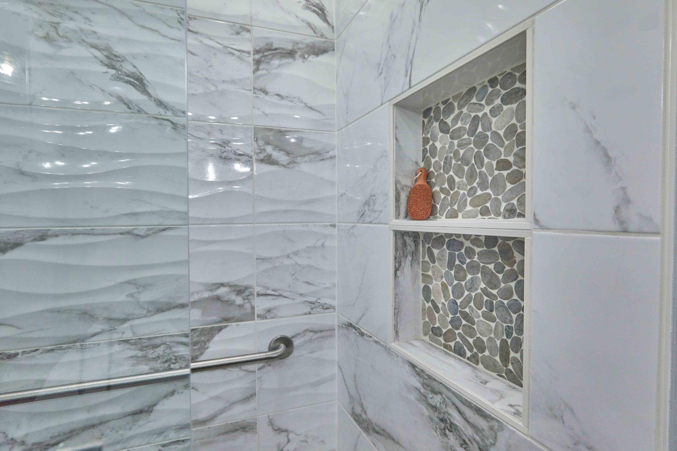 Remodeled basement bathroom walk-in shower featuring a product nook with stone backsplash in Tigard, OR by Creekstone Design + Remodel