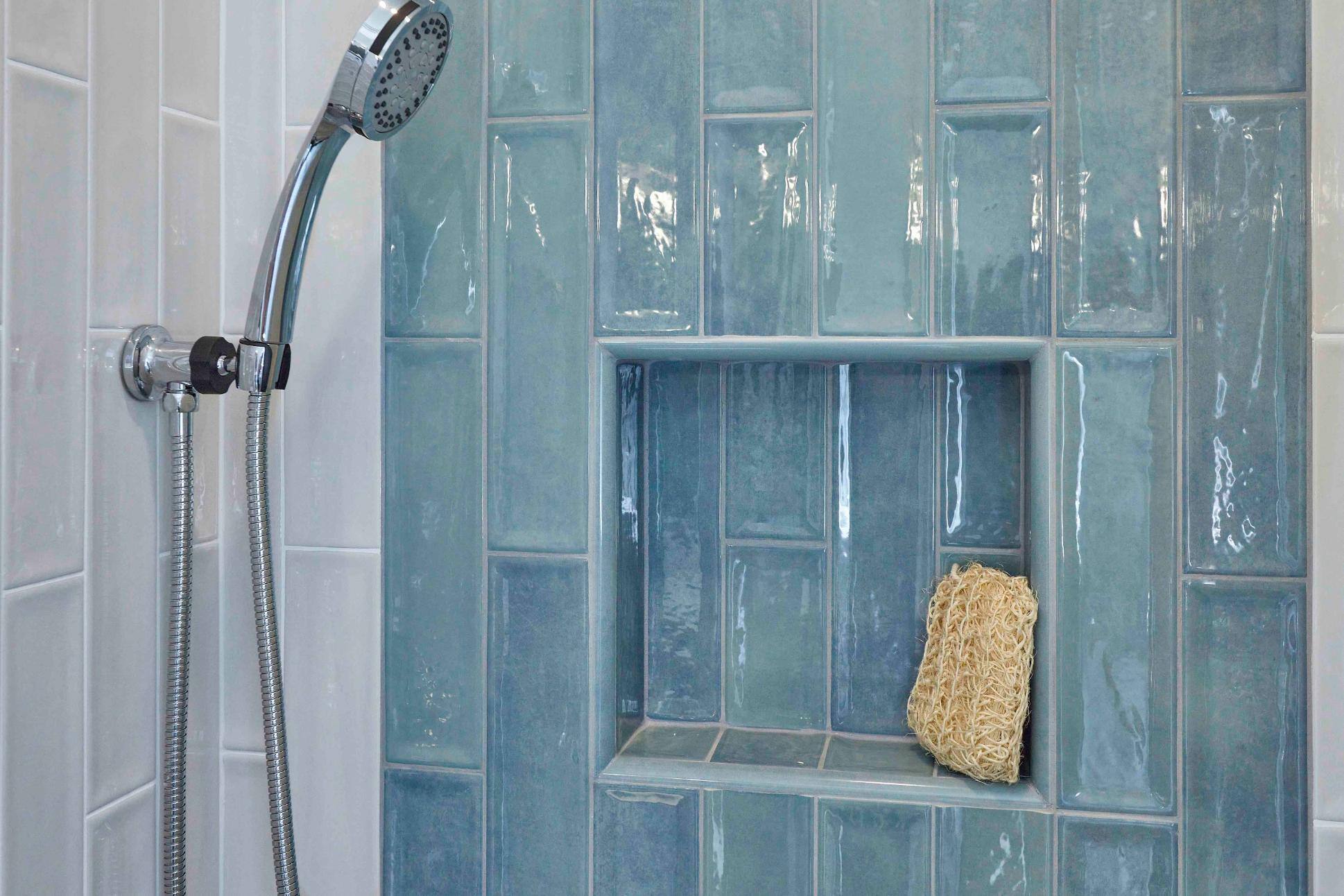 Remodeled bathroom shower with blue and white tile and small product nook in Tigard, OR by Creekstone Design + Remodel