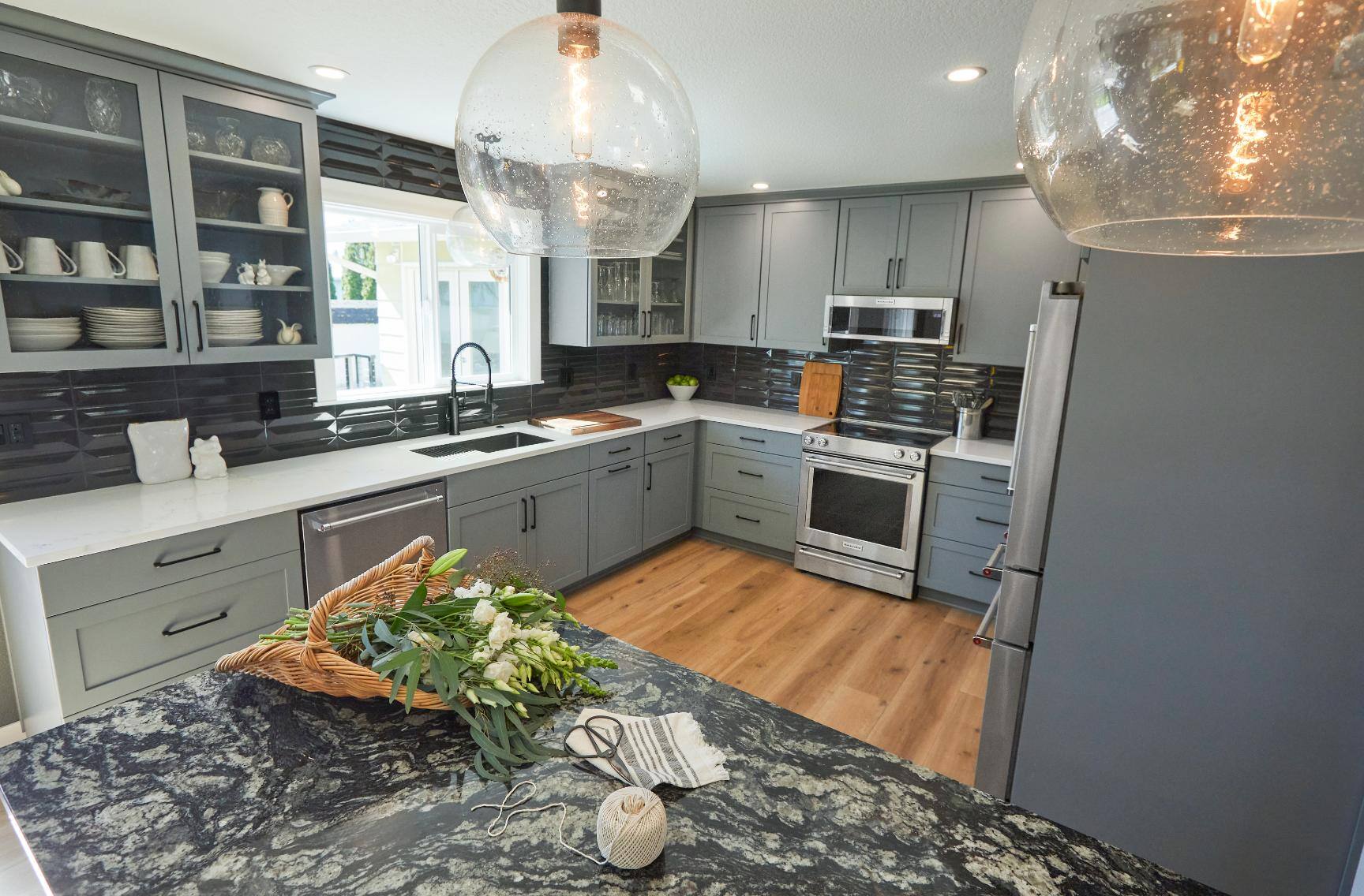 Modern remodeled kitchen with gray cabinetry and black backsplash in Tigard, OR by Creekstone Design + Remodel